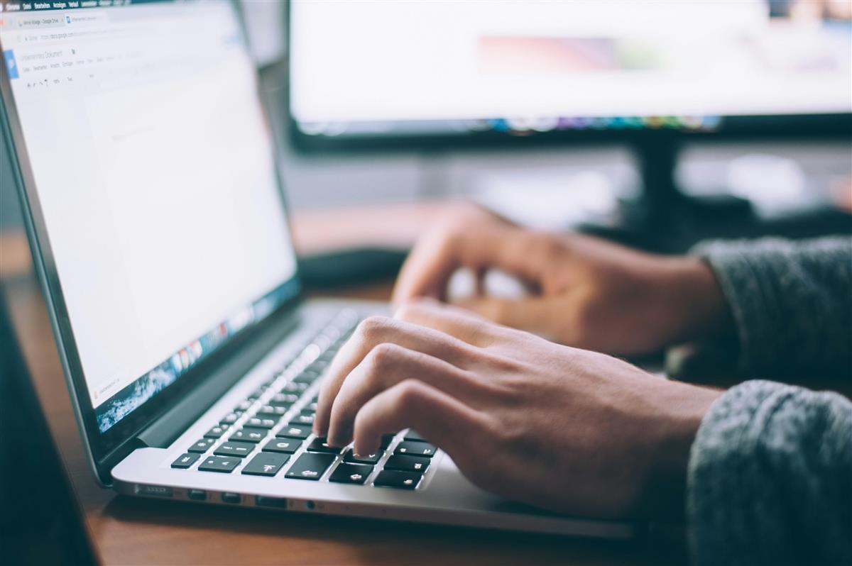 PC-skjerm og hender som skriver på tastatur - Klikk for stort bilde
